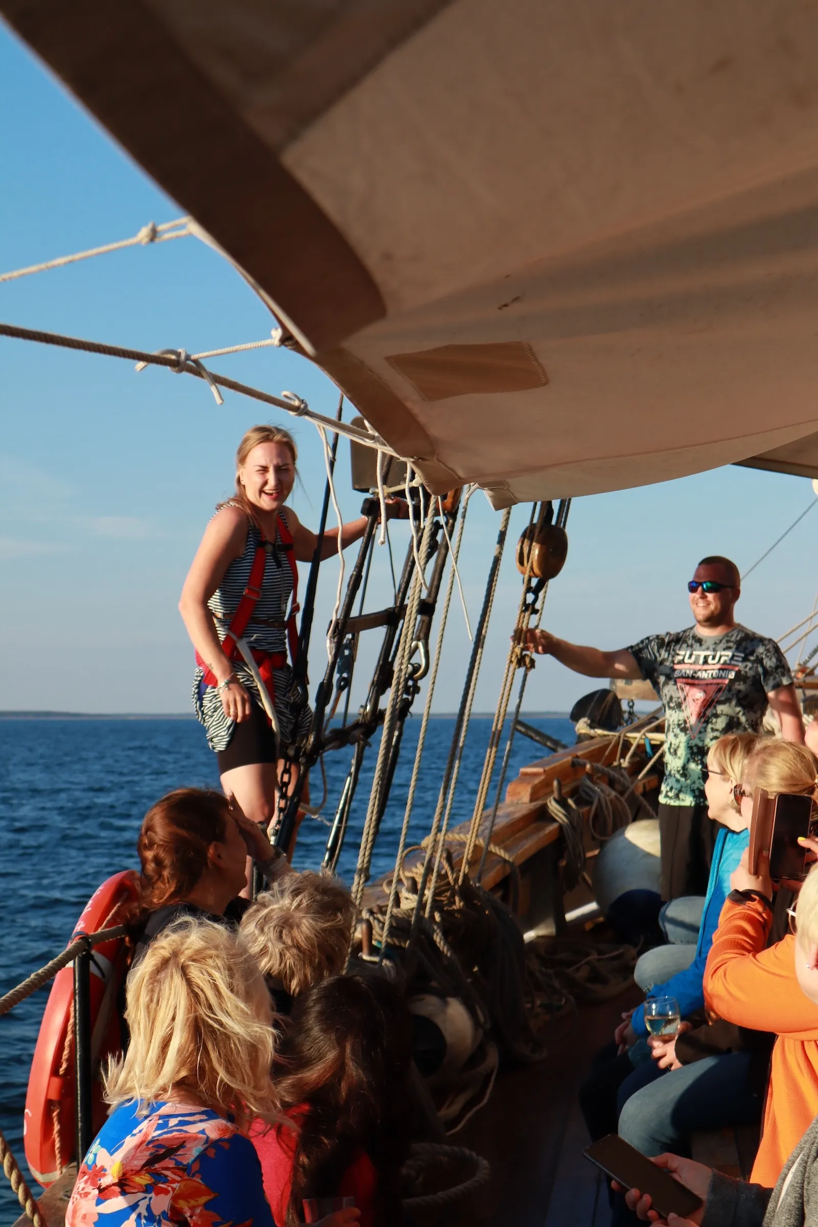 Group enjoying a sailing trip on a traditional Estonian vessel during a sunny day, with participants on deck and sea views in the background